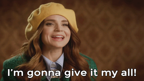Women looking preppy in a yellow beret and green coat saying, 'I'm gonna give it my all'