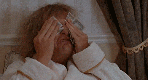 man rubbing dollar bills on his face