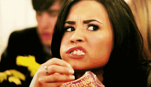 GIF of Demi Lovato shoving popcorn into her mouth angrily