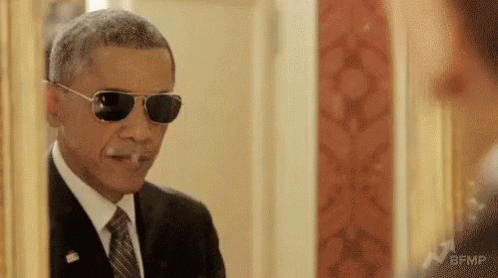 Barak Obama looking in a mirror with sunglasses on, pointing gun fingers in the mirror. Caption says 'change'.