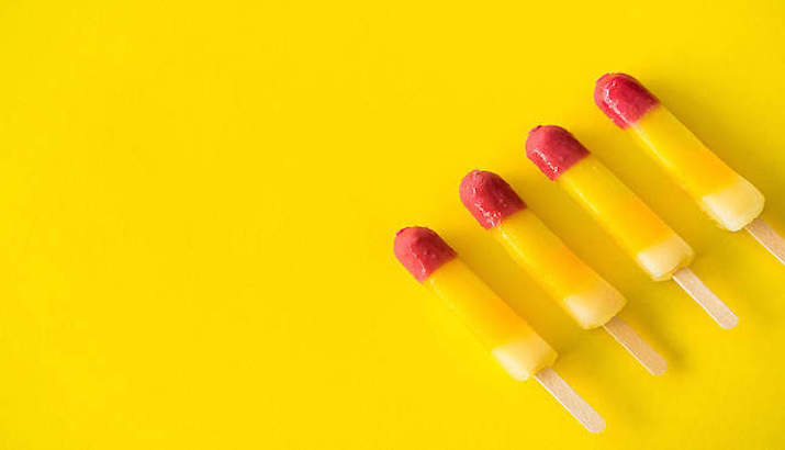 Four red and yellow ice lollies on a yellow background